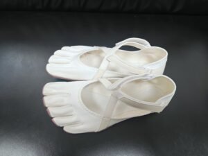 Dancer performing a controlled turn in five toe dance shoes on a studio floor